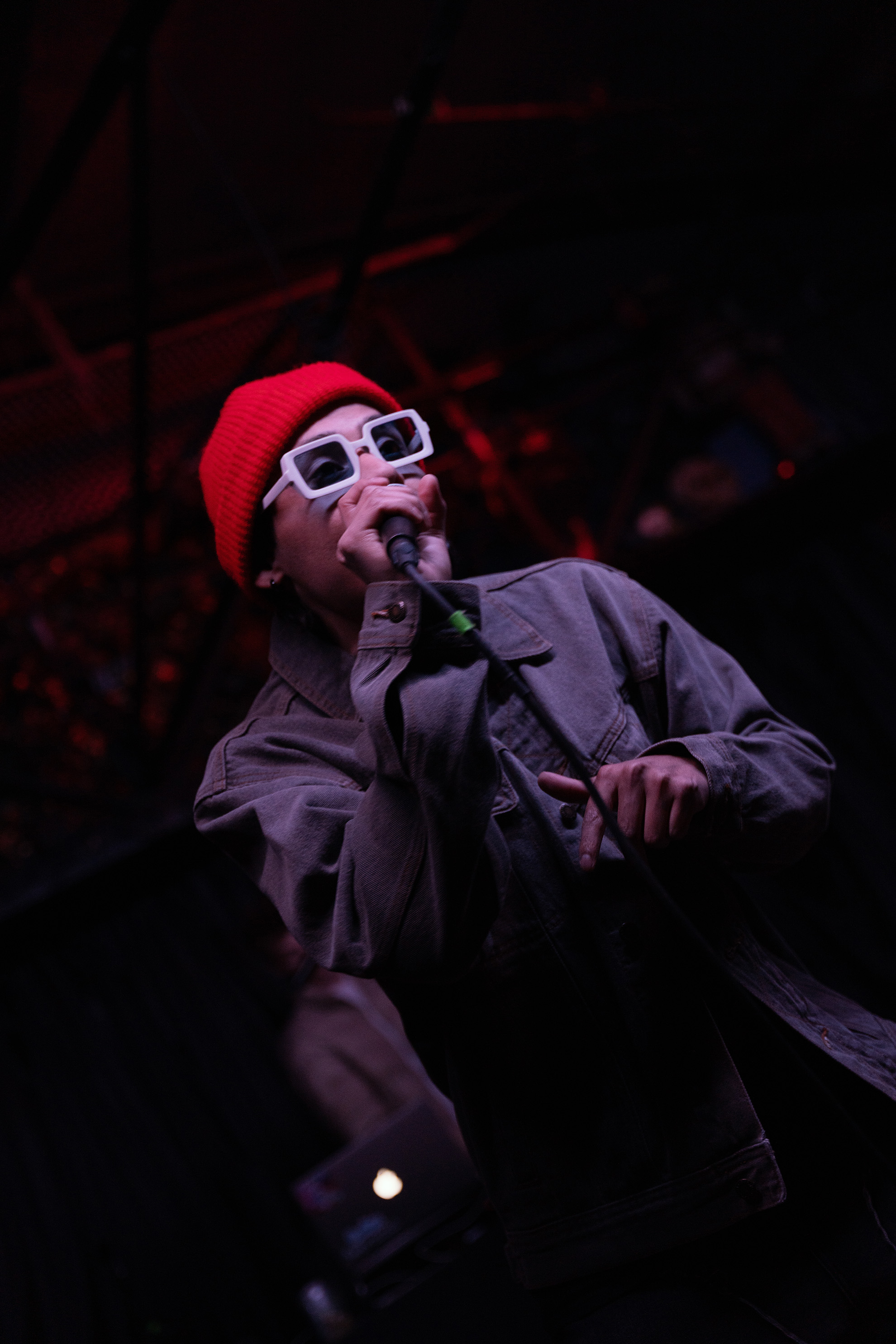 Rapper in a orange beanie and white sunglasses, rapping to the crowd