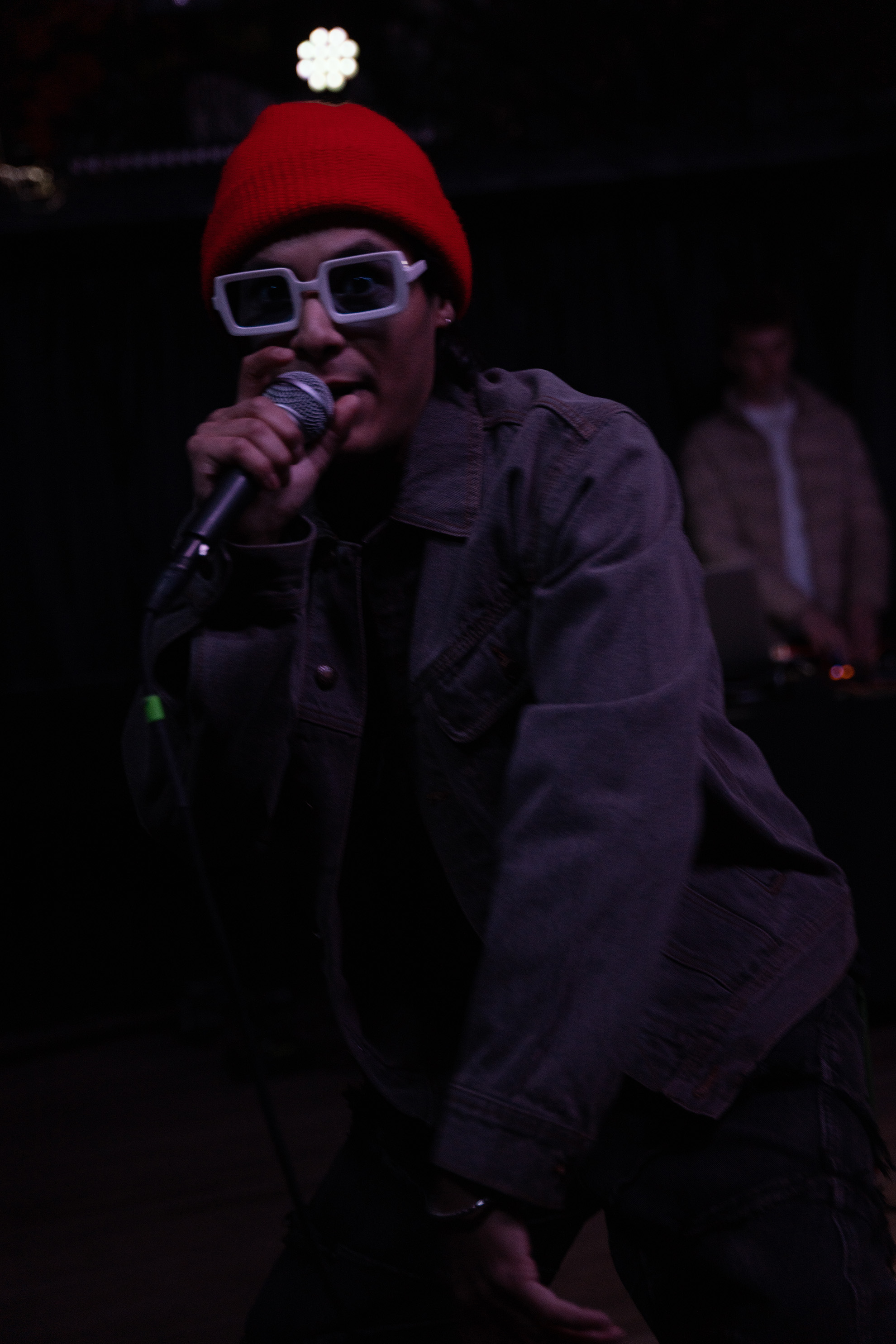 Rapper in a orange beanie and white sunglasses, rapping to the crowd