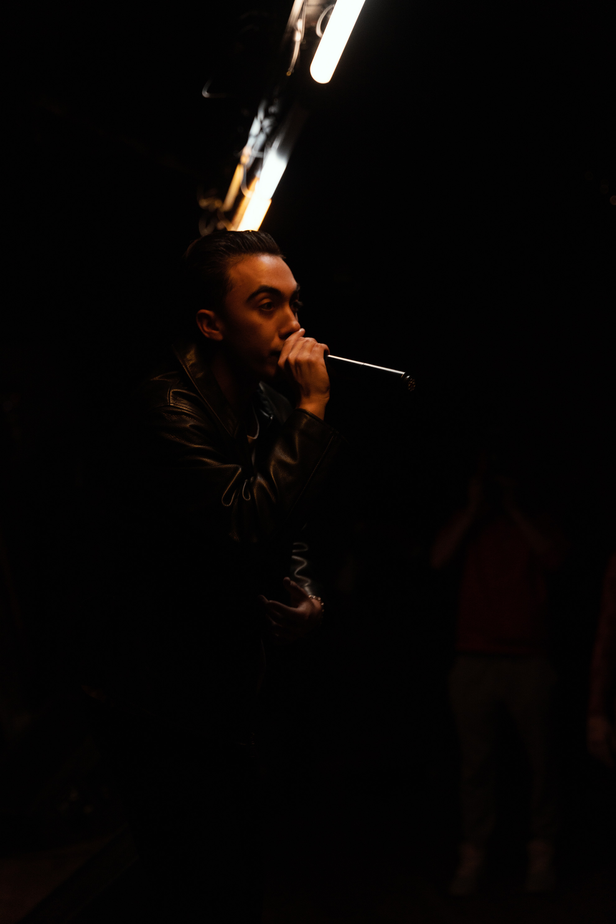 Miguel Crandell rapping within the pit to the crowd in an orange lighting